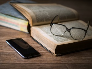 Image shows a smartphone next to a large book