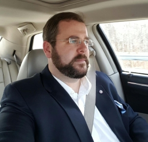 Jeff wears a suit and sits in the driver's seat of a Chrysler